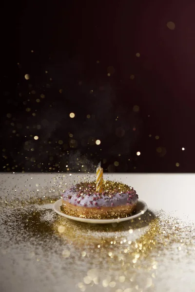 Candle in middle of doughnut with golden shiny sparkles isolated on black — Stock Photo