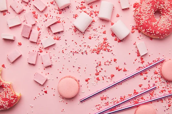 Top view of sweet macaroons, marshmallows and candies isolated on pink — Stock Photo