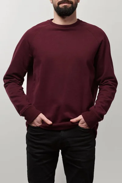 Partial view of man with hands in pockets in burgundy sweatshirt with copy space isolated on grey — Stock Photo
