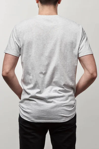 Vista trasera del hombre en camiseta blanca casual con espacio de copia aislado en gris - foto de stock