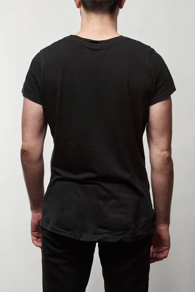 Vista trasera del hombre en camiseta negra con espacio de copia aislado en gris - foto de stock