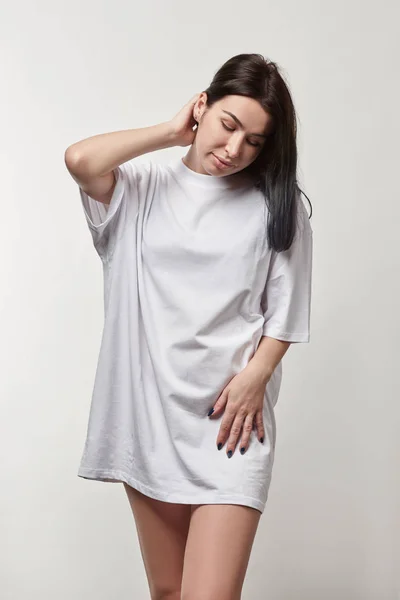 Beautiful young woman in white oversize t-shirt with copy space isolated on grey — Stock Photo