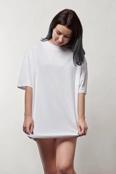 Beautiful young woman in white oversize t-shirt with copy space isolated on grey — Stock Photo