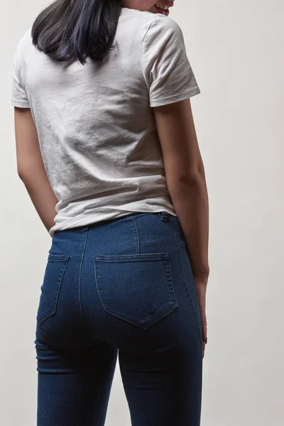 Vista posterior de mujer joven en mezclilla y camiseta blanca con espacio de copia aislado en blanco - foto de stock