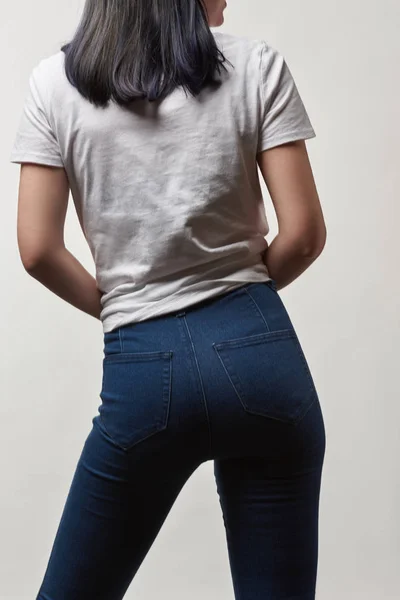 Vista posterior de mujer joven en mezclilla y camiseta blanca con espacio de copia aislado en blanco - foto de stock