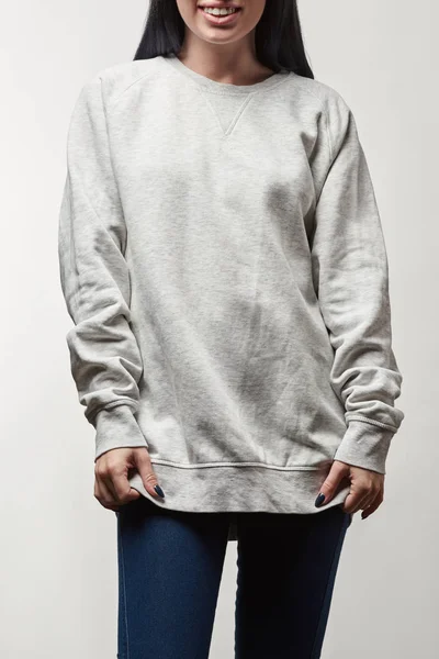 Vista recortada de la joven sonriente en sudadera con capucha gris con espacio de copia aislado en blanco - foto de stock