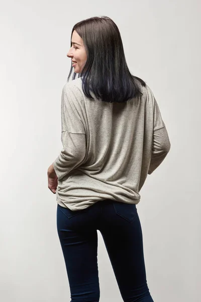 Vista trasera de mujer joven en manga larga gris con espacio de copia aislado en blanco - foto de stock