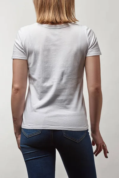 Vista trasera de mujer joven en camiseta blanca casual con espacio de copia aislado en blanco - foto de stock