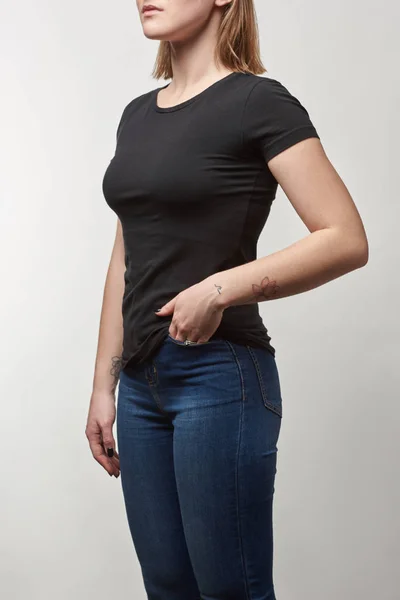 Обрезанный вид молодой женщины в черной футболке с копировальным пространством, изолированным на белом — стоковое фото