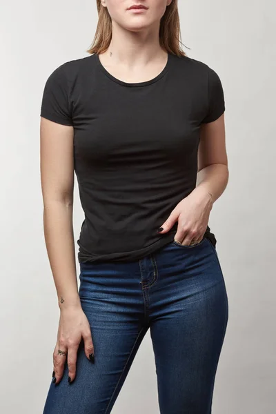 Partial view of young woman with hand in pocket in black t-shirt with copy space isolated on white — Stock Photo