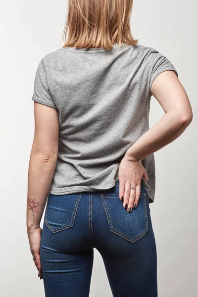 Vista trasera de la joven en camiseta gris con espacio de copia aislado en blanco - foto de stock