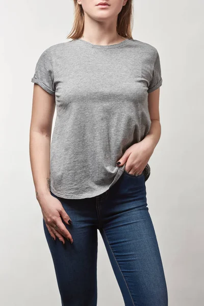 Vue recadrée de jeune femme avec la main dans la poche en t-shirt gris avec espace de copie isolé sur blanc — Photo de stock