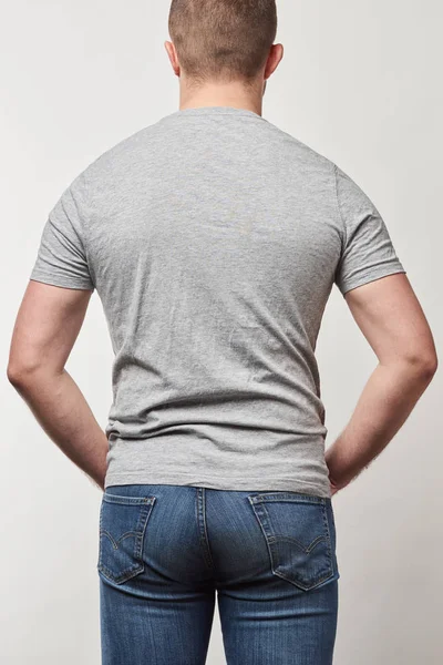 Vista trasera del hombre en mezclilla y camiseta con espacio de copia aislado en gris - foto de stock