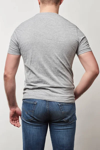 Vista trasera del hombre en mezclilla y camiseta con espacio de copia aislado en gris - foto de stock