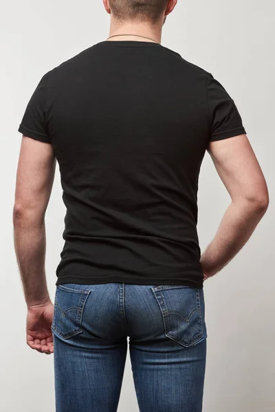 Vista posteriore dell'uomo in t-shirt nera con spazio copia isolato su grigio — Foto stock