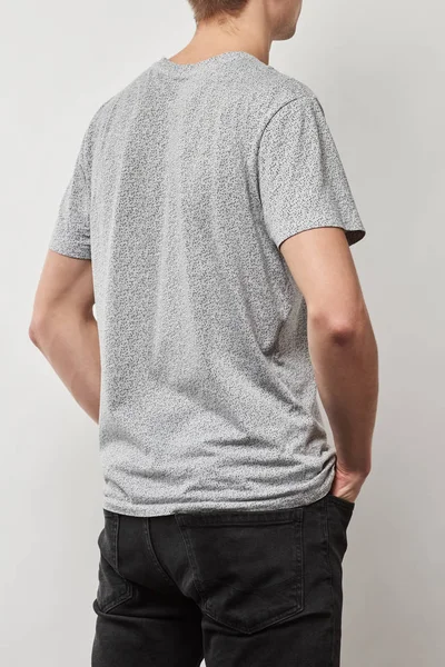 Задний вид человека в футболке с копировальным пространством, изолированным на сером — стоковое фото