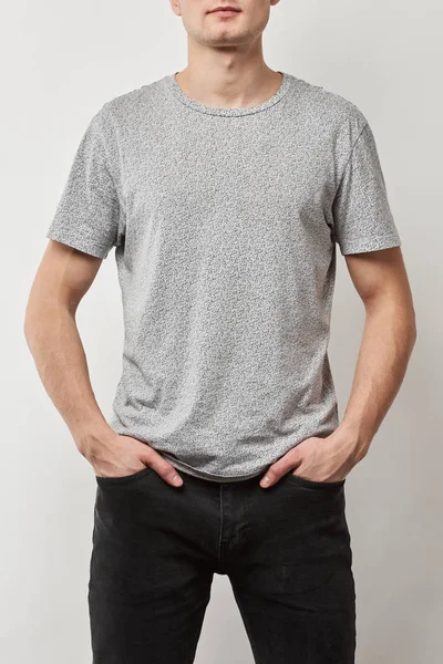 Partial view of man with hands in pockets in t-shirt with copy space isolated on grey — Stock Photo