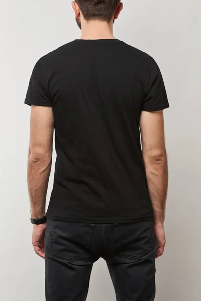 Vue arrière de l'homme en t-shirt noir avec espace de copie isolé sur gris — Photo de stock