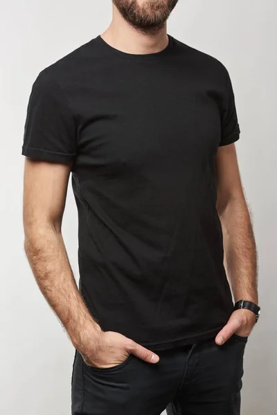 Обрезанный вид человека в основной черной футболке с копировальным пространством, изолированным на белом — стоковое фото