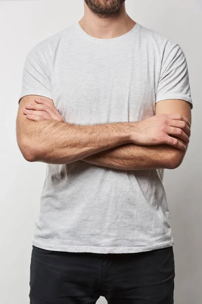 Partial view of man with arms crossed in white t-shirt with copy space isolated on grey — Stock Photo