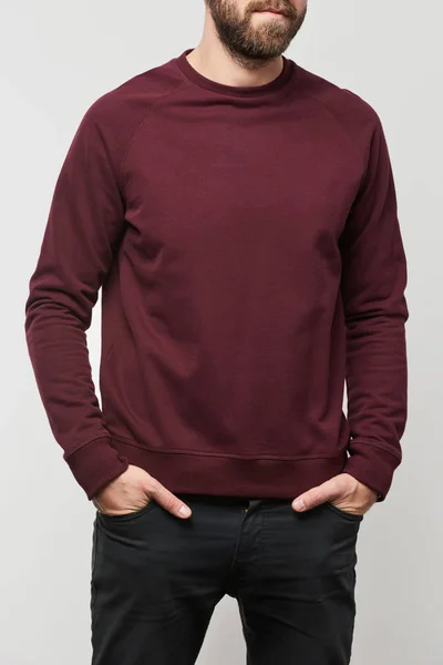 Partial view of man with hands in pockets in burgundy sweatshirt with copy space isolated on grey — Stock Photo