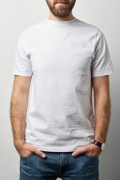 Vista ritagliata dell'uomo con le mani in tasche in t-shirt bianca con spazio copia isolato su grigio — Foto stock