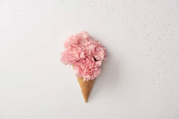 Beautiful pink carnation flowers in waffle cone isolated on grey — Stock Photo