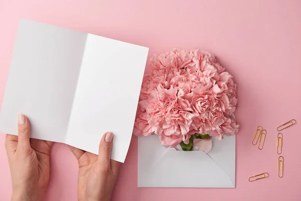 Abgeschnittene Aufnahme einer Frau mit leerer Karte und rosa Blumen im Umschlag, isoliert auf rosa — Stockfoto