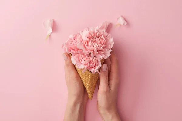 Plan recadré de femme tenant un cône de gaufrettes avec de belles fleurs tendres isolées sur rose — Photo de stock