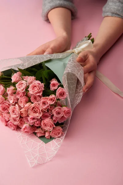 Vista parcial de la mujer sosteniendo ramo de hermosas rosas en rosa - foto de stock