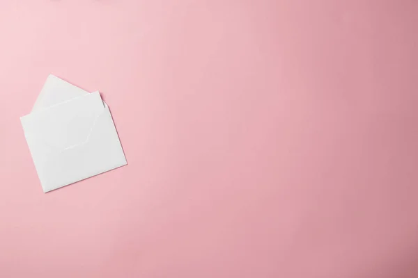Vista superior del sobre blanco con tarjeta de felicitación en blanco aislada sobre fondo rosa - foto de stock