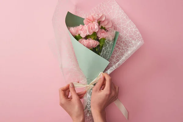 Cropped shot of woman tying beautiful tender flower bouquet isolated on pink — Stock Photo