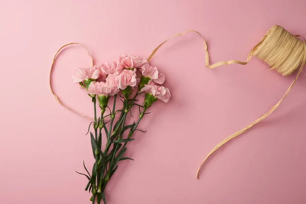 Draufsicht auf schöne rosa Nelkenblüten und Band isoliert auf rosa — Stockfoto