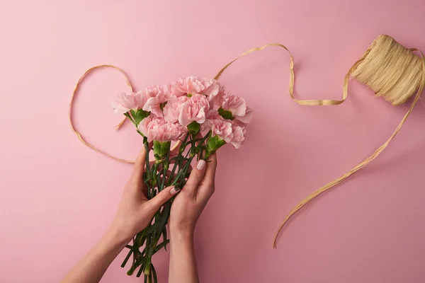 Colpo ritagliato di donna che tiene fiori di garofano rosa isolati su rosa — Foto stock