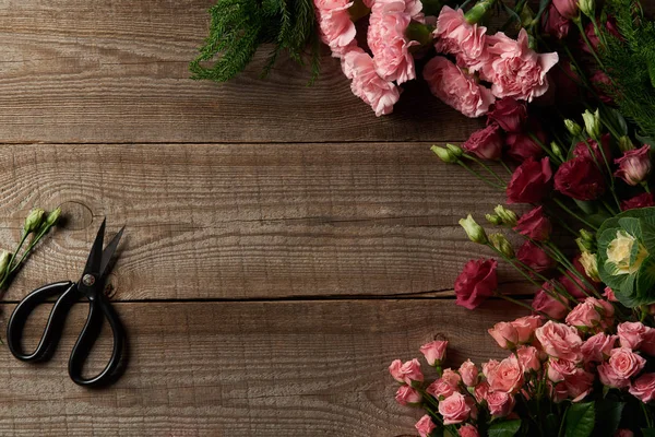 Top view of beautiful various red and pink flowers and scissors on wooden table — Stock Photo