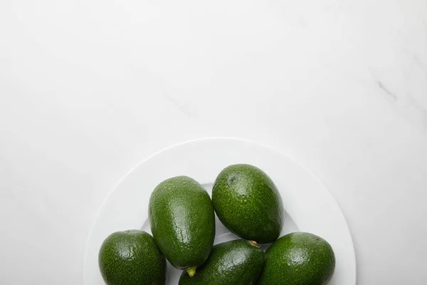 Вид сверху на авокадо в пластине на сером текстурированном фоне — стоковое фото