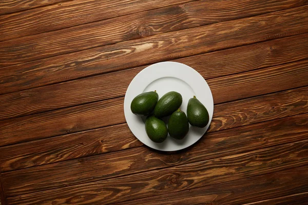 Vista dall'alto di avocado in piatto su fondo di legno — Foto stock