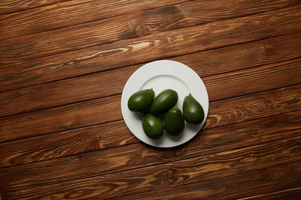 Vista superior de aguacates en plato sobre fondo de madera - foto de stock