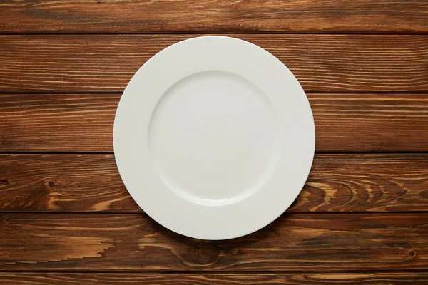 Top view of white empty plate on wooden background — Stock Photo