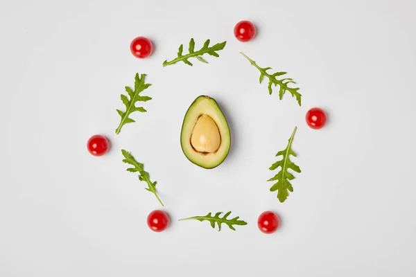 Vista dall'alto di avocado, foglie di arugola e pomodorini su sfondo grigio — Foto stock