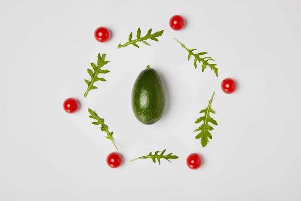 Вид зверху на авокадо, листя рук і помідори вишні на сірому фоні — стокове фото