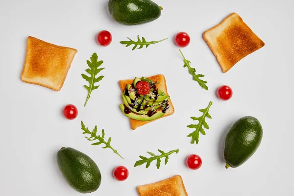 Top view of toasts with avocados, cherry tomatoes and arugulas leaves on grey background — Stock Photo