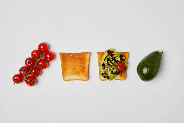 Top view of toasts with avocados and cherry tomatoes on grey background — Stock Photo