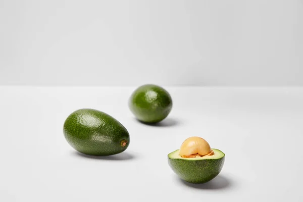 Enfoque selectivo de aguacates sobre fondo gris - foto de stock