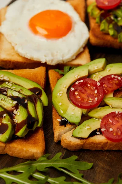 Избирательный фокус тостов с омлетом, помидорами черри и авокадо на деревянном фоне — стоковое фото