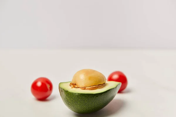 Селективний фокус на різанні авокадо та вишневих помідорів на сірому фоні — стокове фото
