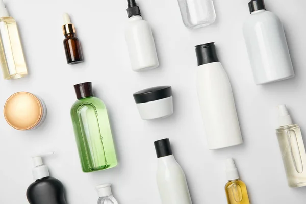 Vista superior de várias garrafas e recipientes de cosméticos em fundo branco — Fotografia de Stock