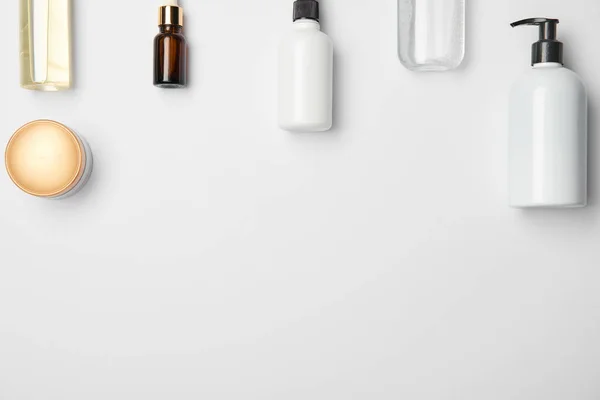 Vista superior de diferentes garrafas cosméticas no fundo branco com espaço de cópia — Fotografia de Stock