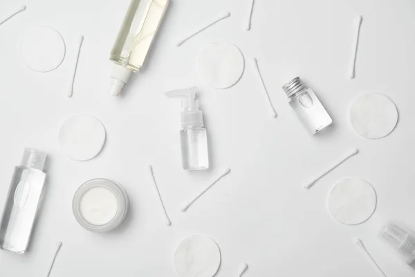 Vue du dessus de différentes bouteilles cosmétiques, bâtons de coton et tampons cosmétiques sur fond blanc — Photo de stock