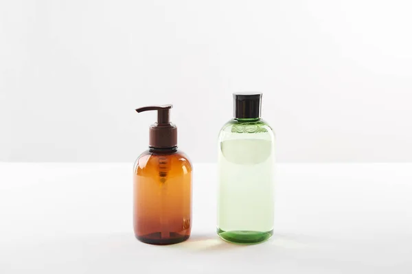 Distributeur cosmétique avec lotion et flacon de sérum sur surface blanche — Photo de stock